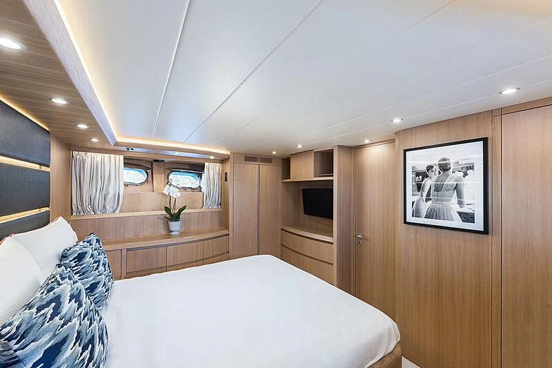a bedroom with a bed and a wood cabinet aboard POBEDY I Yacht for Sale