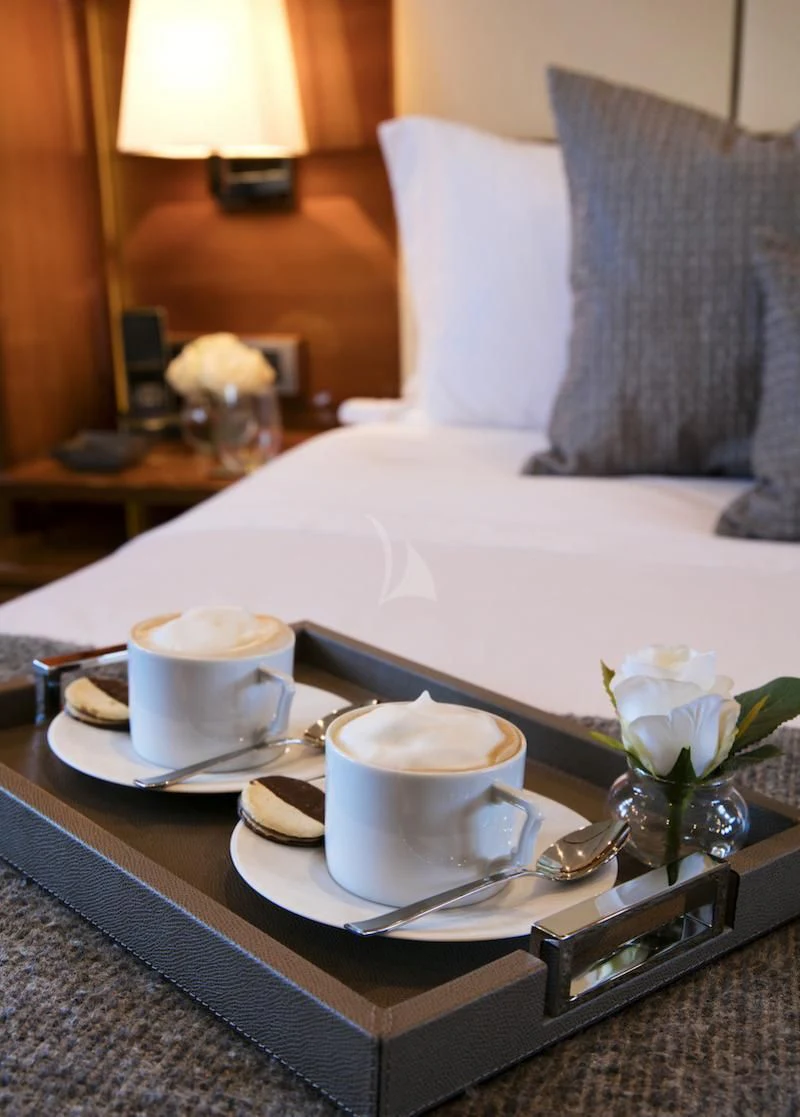 a plate of food and a cup on a bed aboard APMONIA Yacht for Sale