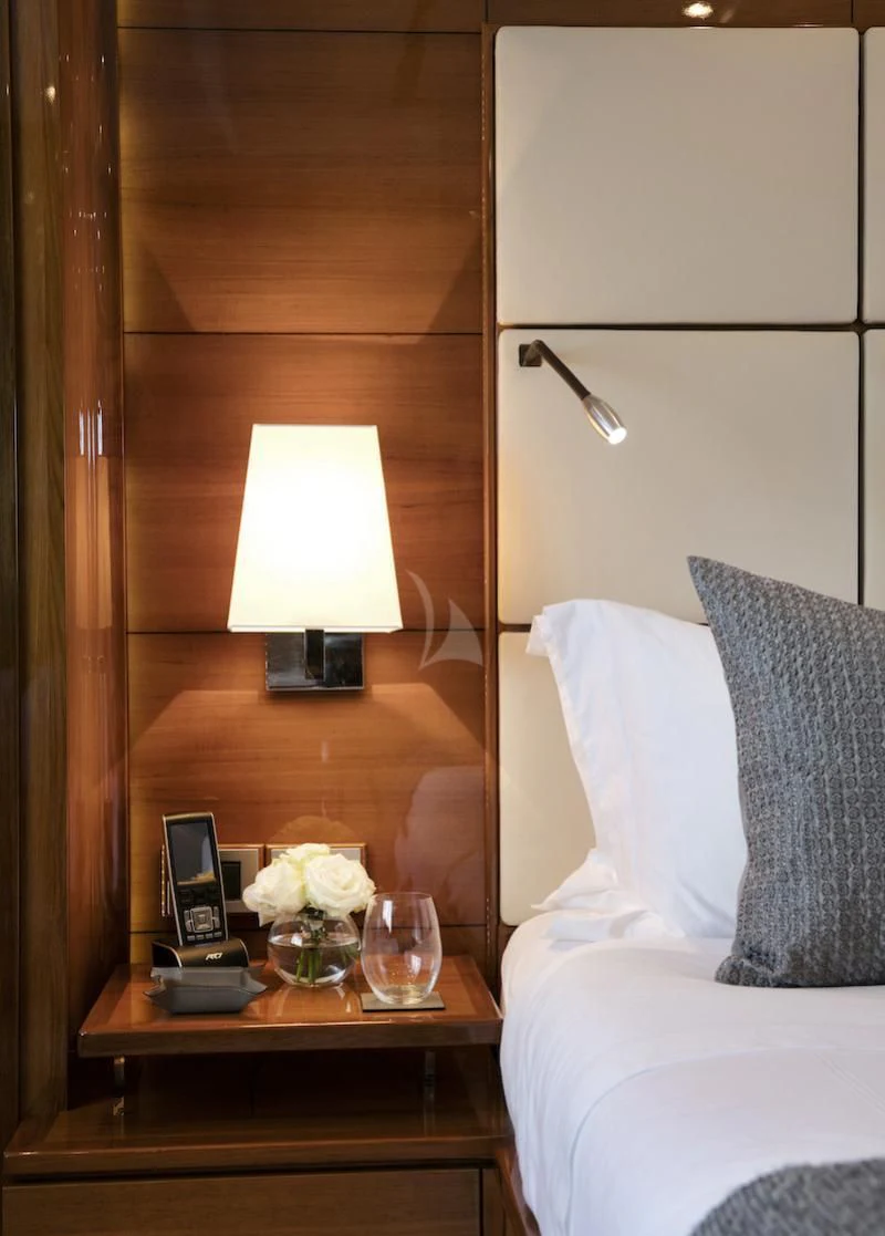 a bed with a table and a lamp on it aboard APMONIA Yacht for Sale