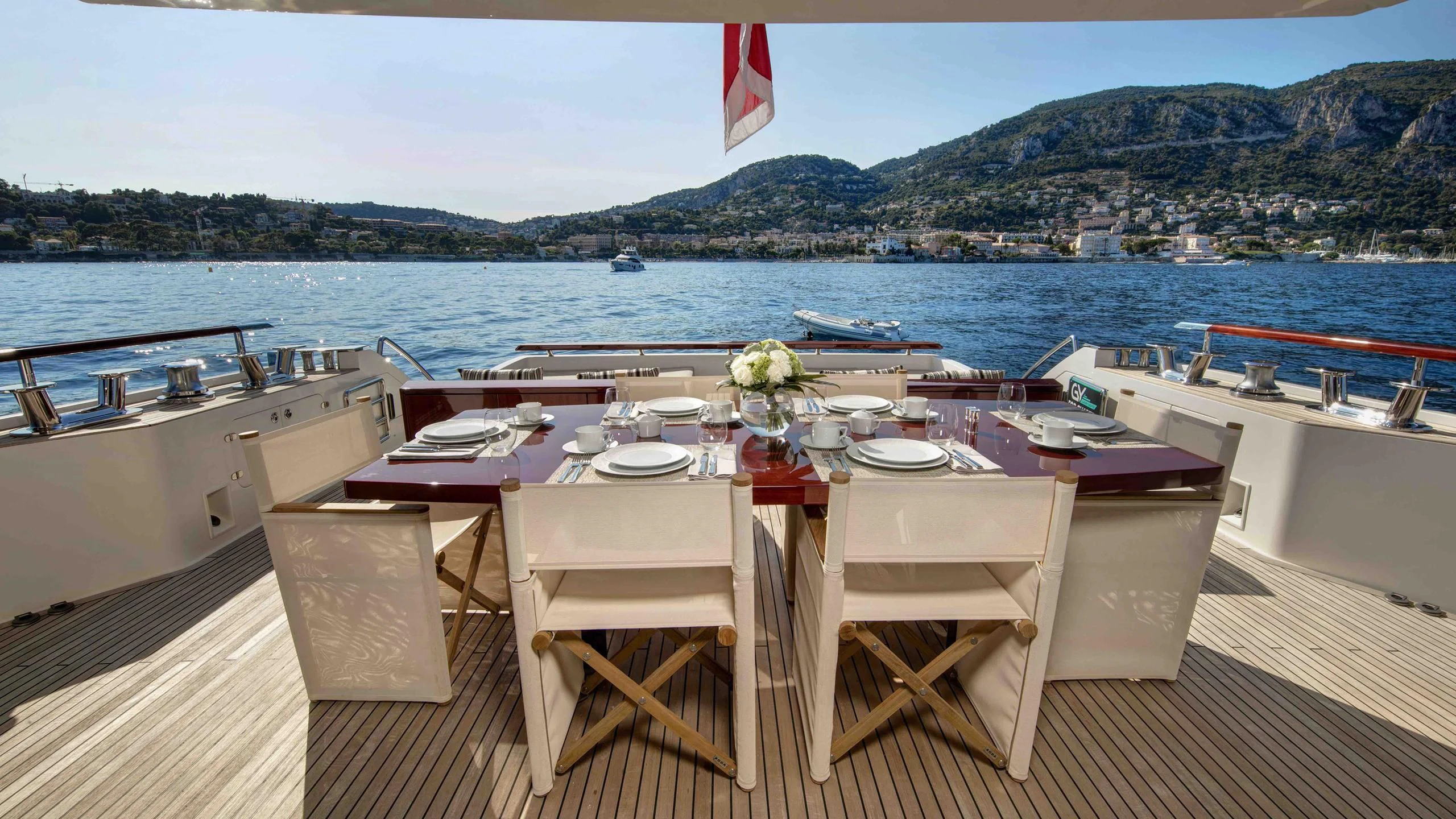 a table set for a dinner on a deck overlooking a large body of water aboard APMONIA Yacht for Sale