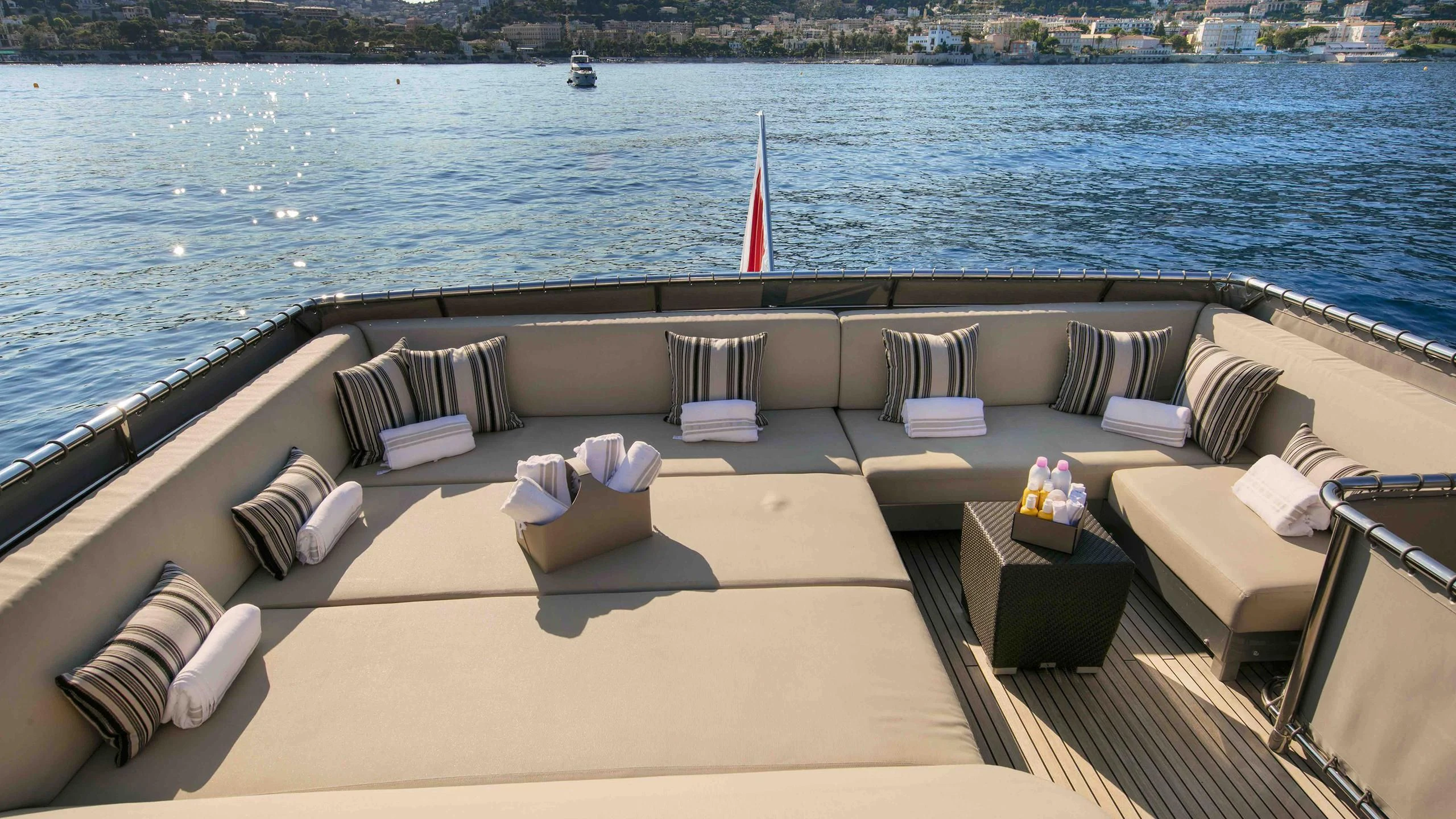 a deck with chairs and pillows on it by a body of water aboard APMONIA Yacht for Sale