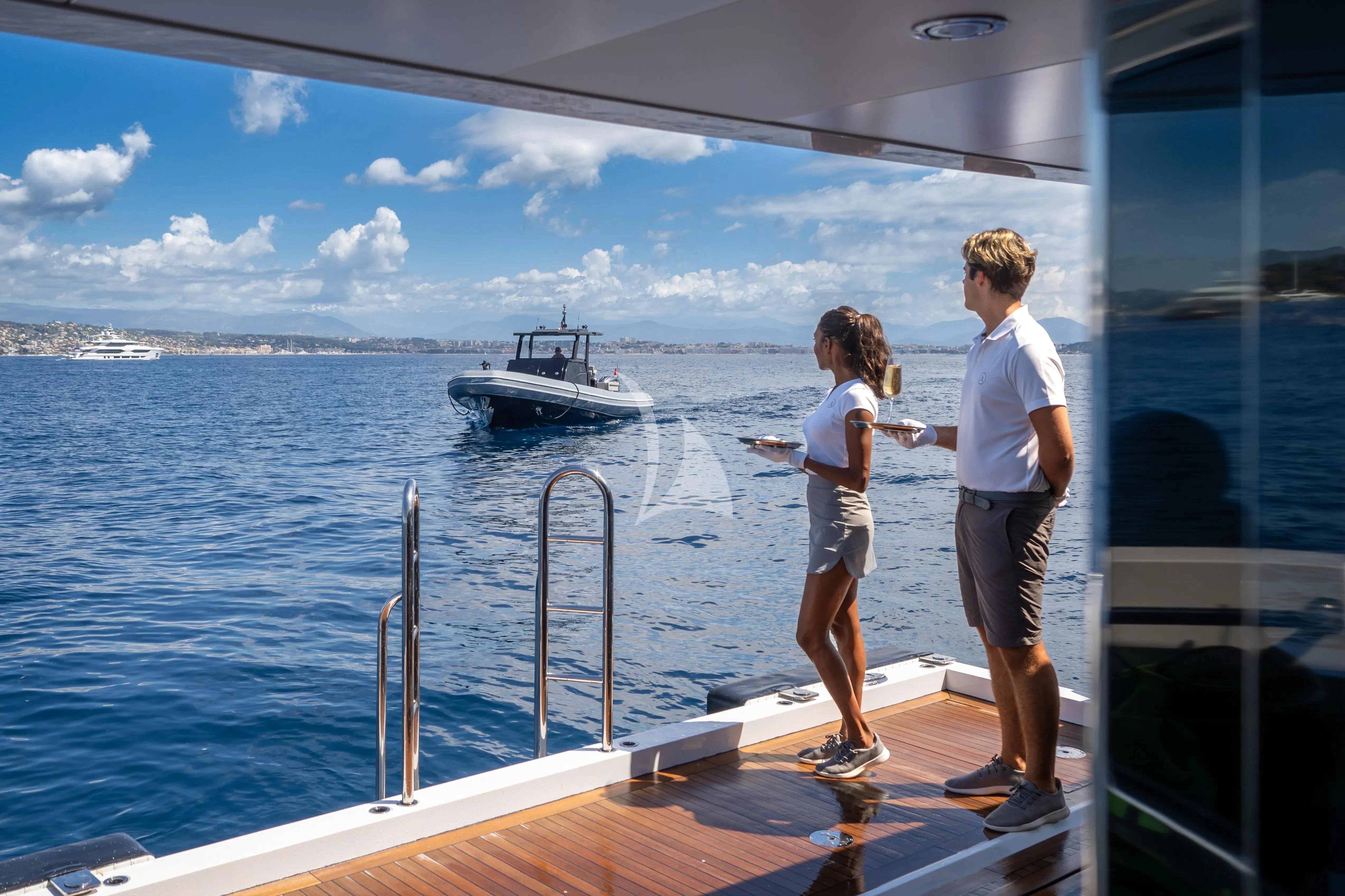 a couple of people on a boat looking at a boat in the water aboard ARADOS Yacht for Charter