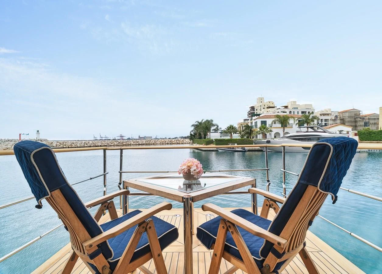 a table and chairs on a deck overlooking a body of water aboard BEOL Yacht for Sale