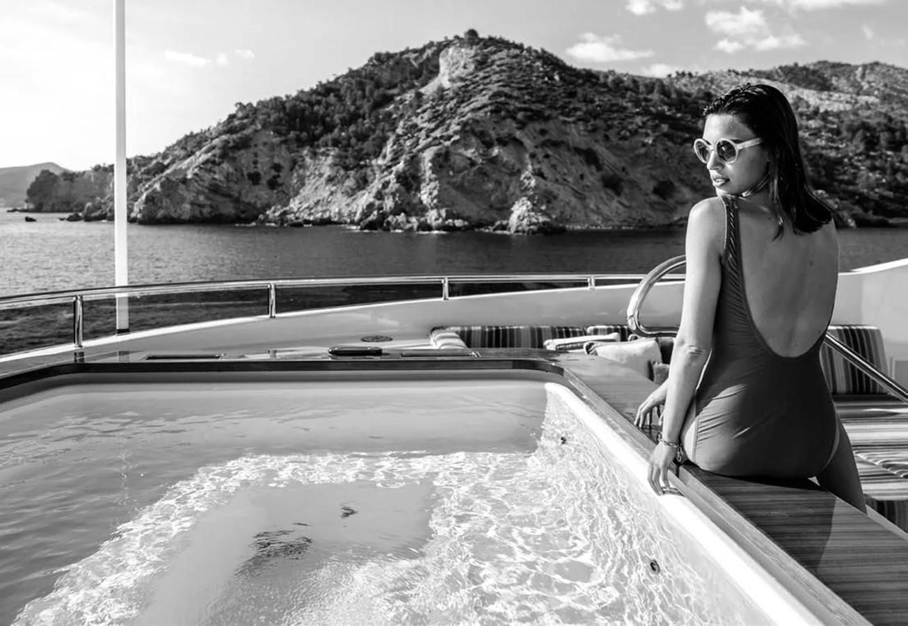 a woman in a swimsuit leaning on a railing on a boat aboard JULIA Yacht for Sale