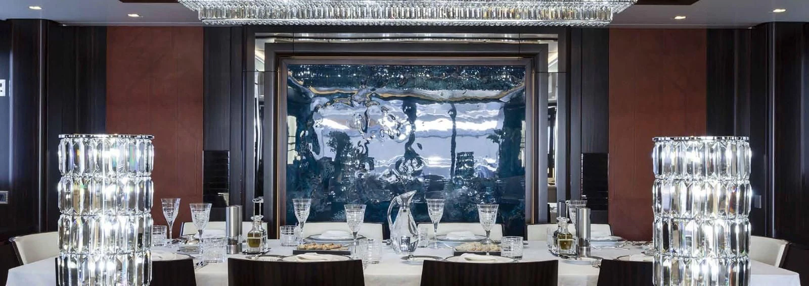 a table with wine glasses and a large screen in the background aboard JULIA Yacht for Sale