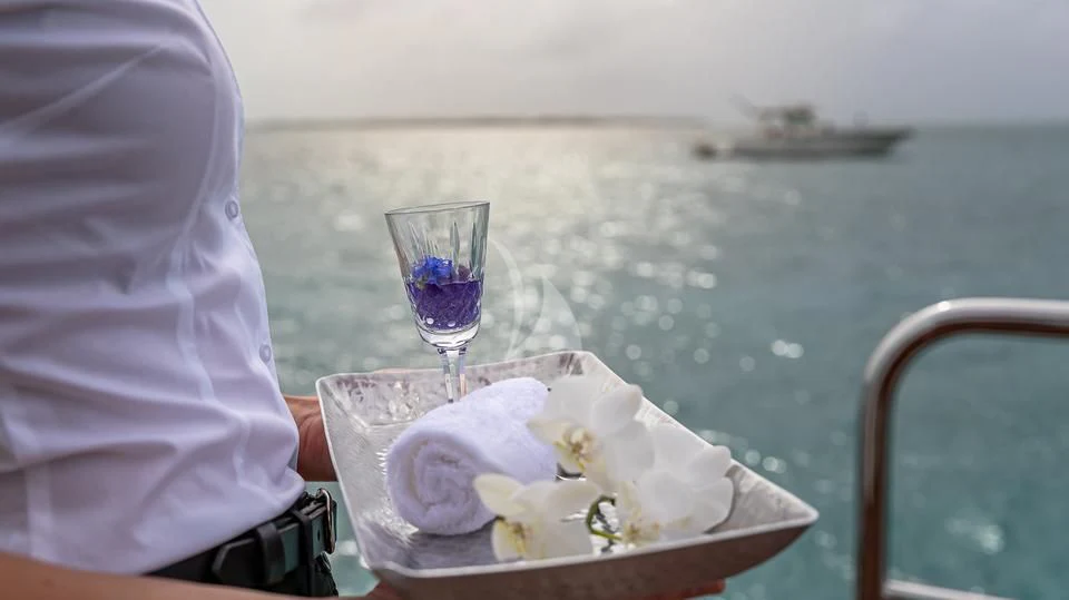 a person sitting at a table with a glass of wine and a flower aboard SILVER LINING Yacht for Sale