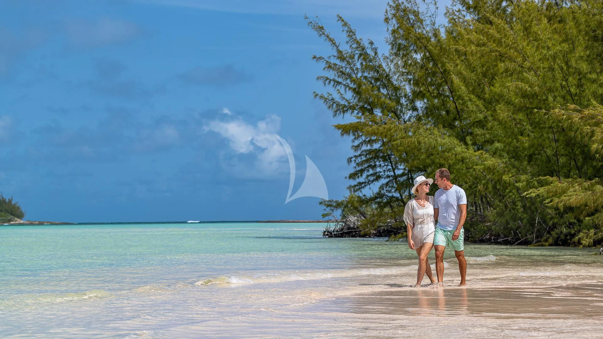 a man and woman standing on a beach with trees and water in the background aboard SILVER LINING Yacht for Sale