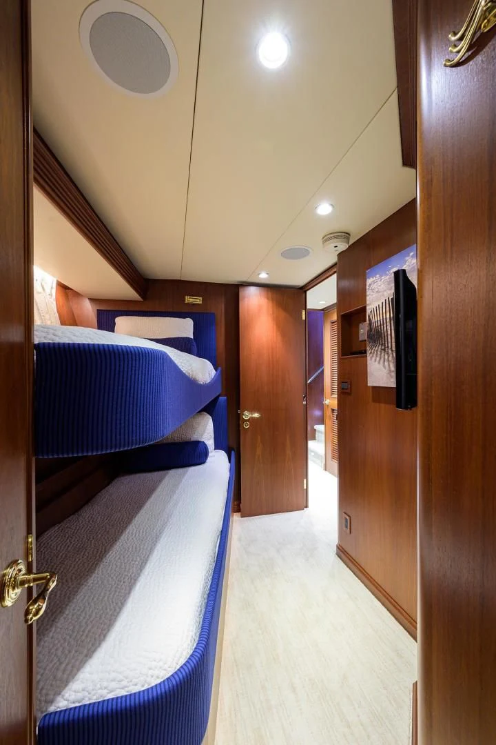 a hallway with a blue bed and a blue chair aboard CHECKERS Yacht for Sale