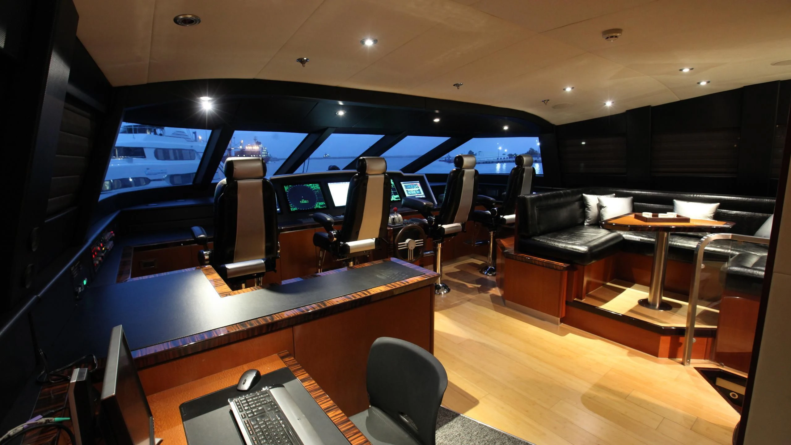 a room with a couch and a table with chairs and a laptop aboard AQUANOVA Yacht for Sale