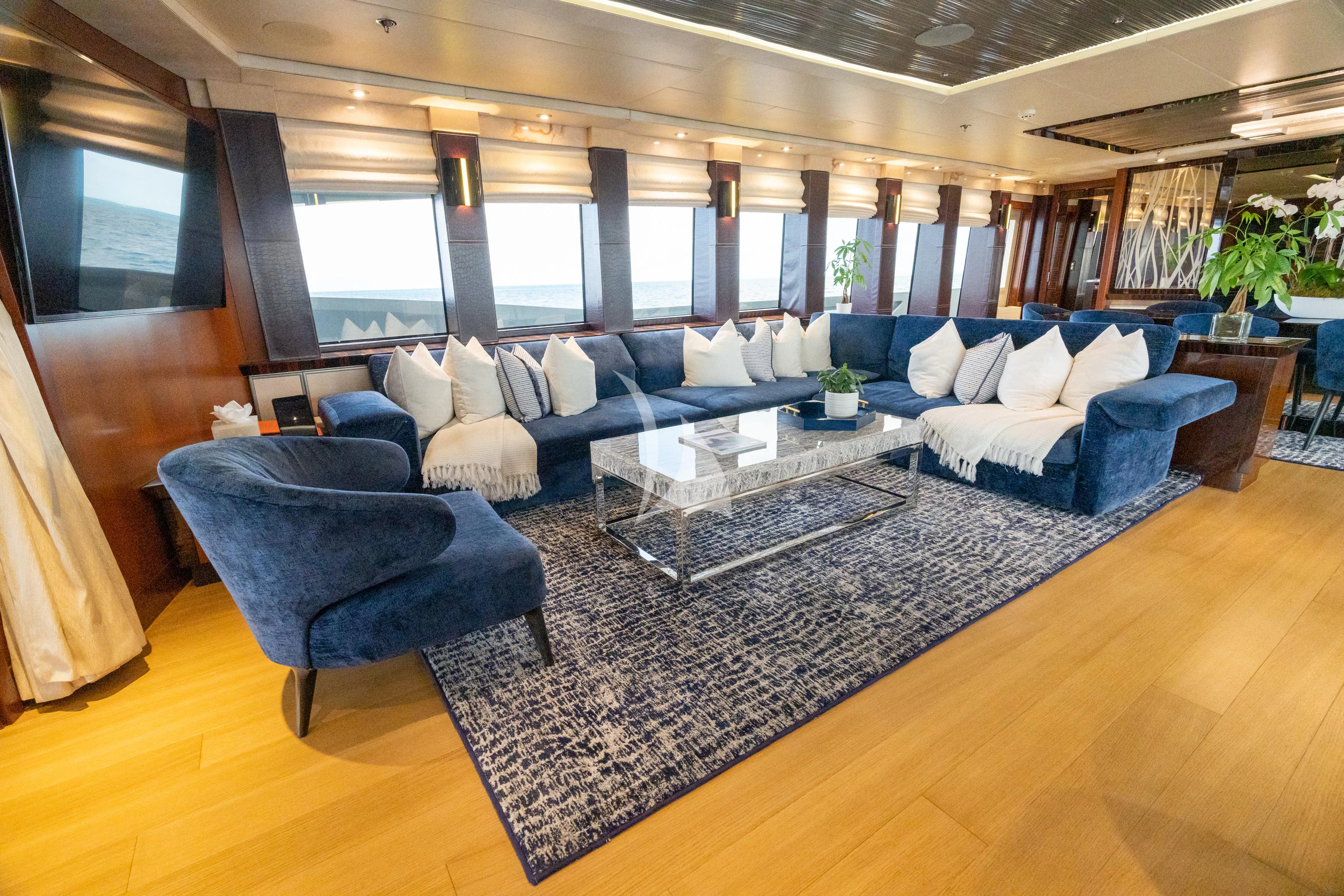 a large living room with a large blue couch and a large rug aboard AQUANOVA Yacht for Sale