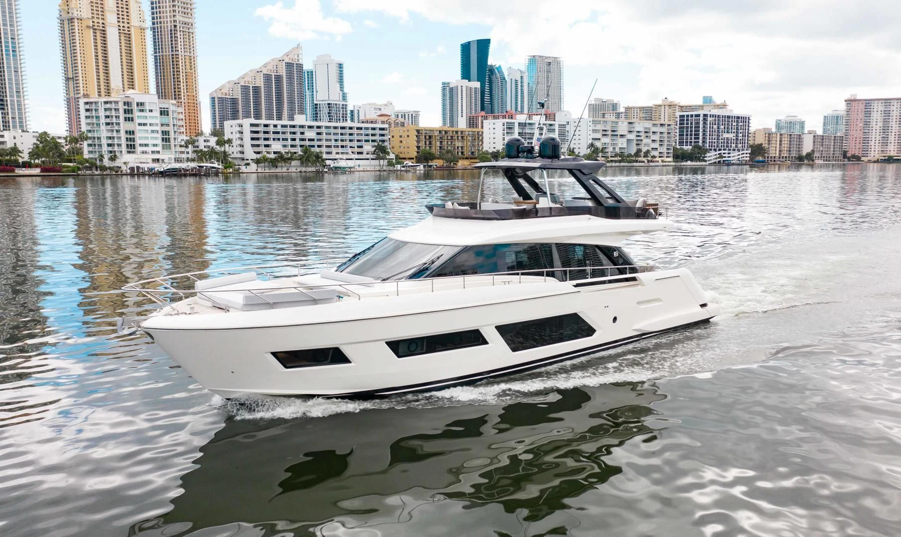 a white boat in a body of water with buildings in the background aboard OUR TRADE Yacht for Sale