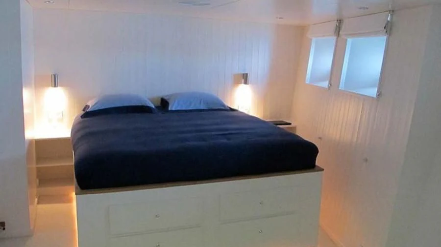 a bed with a black comforter aboard OMNIA Yacht for Sale