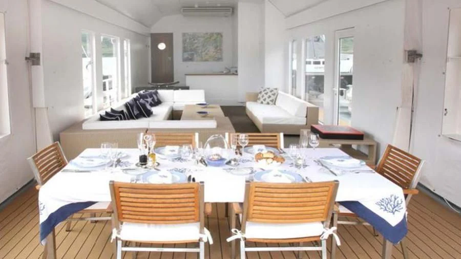 a dining table with a white tablecloth and chairs aboard OMNIA Yacht for Sale
