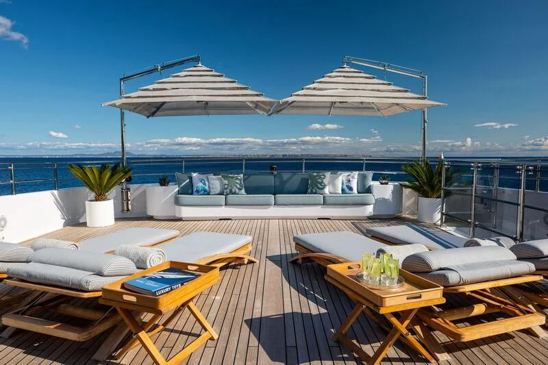 a deck with a table and chairs on it and a large body of water in the background aboard EMERALD (YET) Yacht for Sale