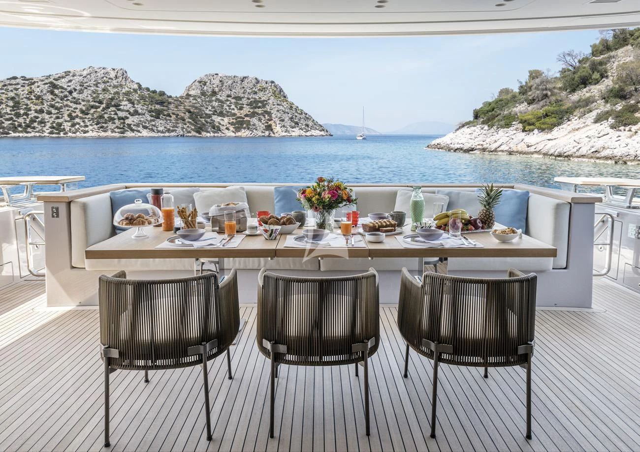 a table set for a meal on a balcony overlooking a body of water aboard FATSA Yacht for Sale