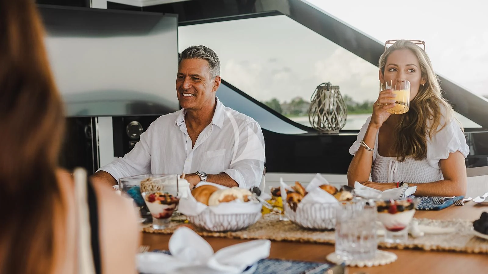 a man and woman sitting at a table with food and drinks aboard KOJU Yacht for Sale