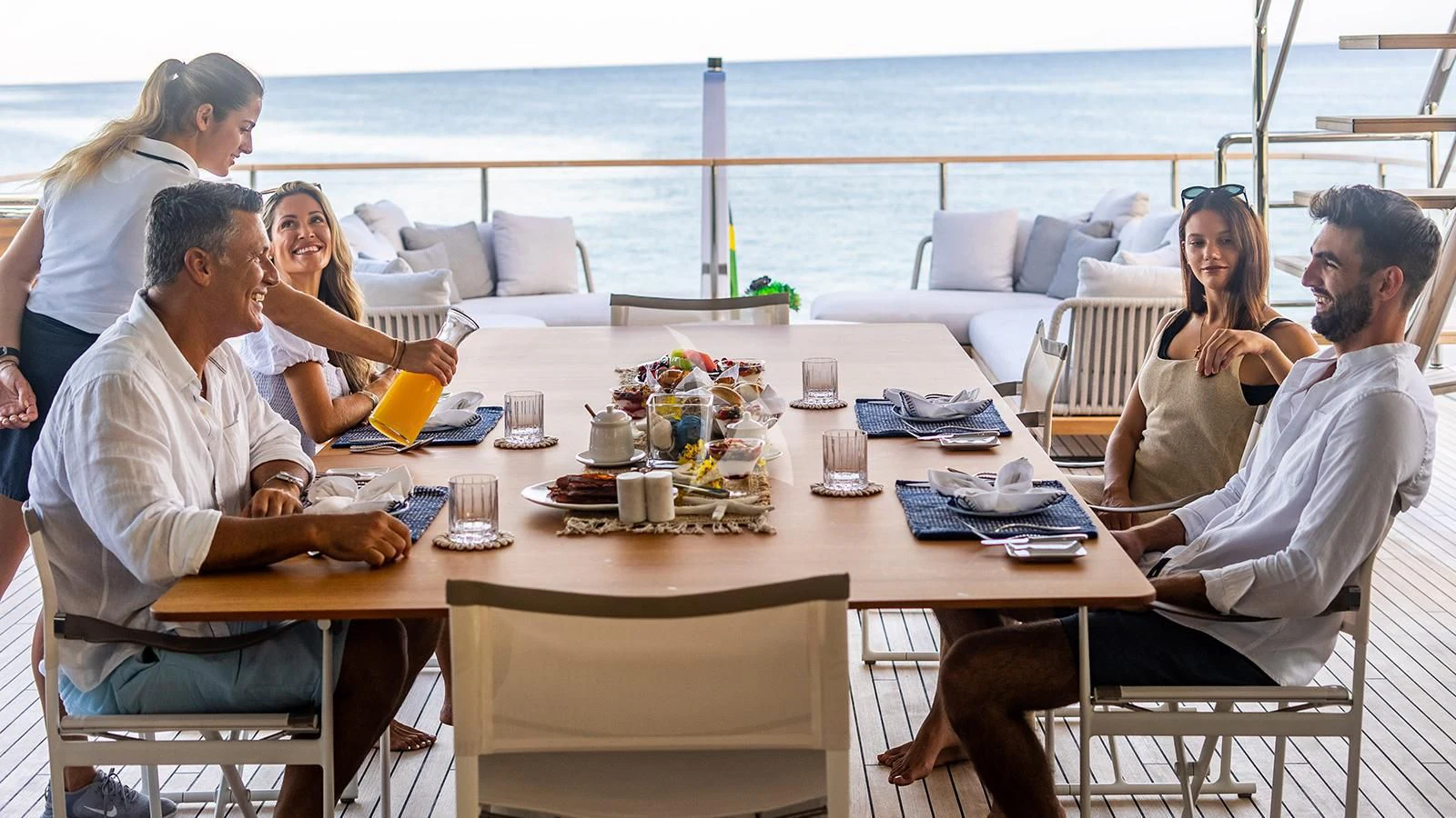 a group of people sitting around a table aboard KOJU Yacht for Sale