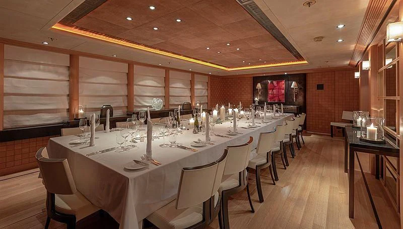 a large room with a table and chairs and a large window aboard KOJU Yacht for Sale