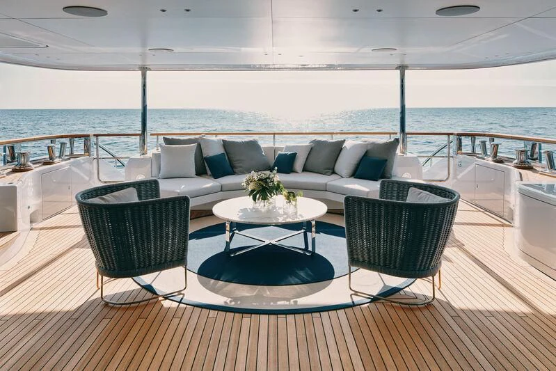 a couch and a table on a balcony overlooking a body of water aboard KOJU Yacht for Sale