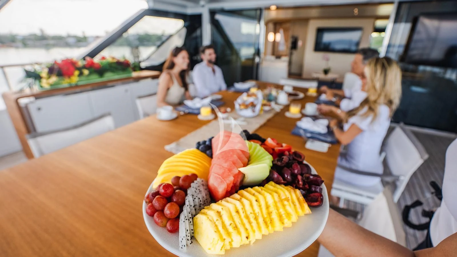 a group of people sitting at a table with food on it aboard KOJU Yacht for Sale