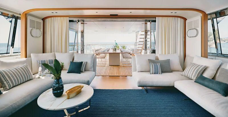 a living room with a large blue rug and white couches aboard KOJU Yacht for Sale