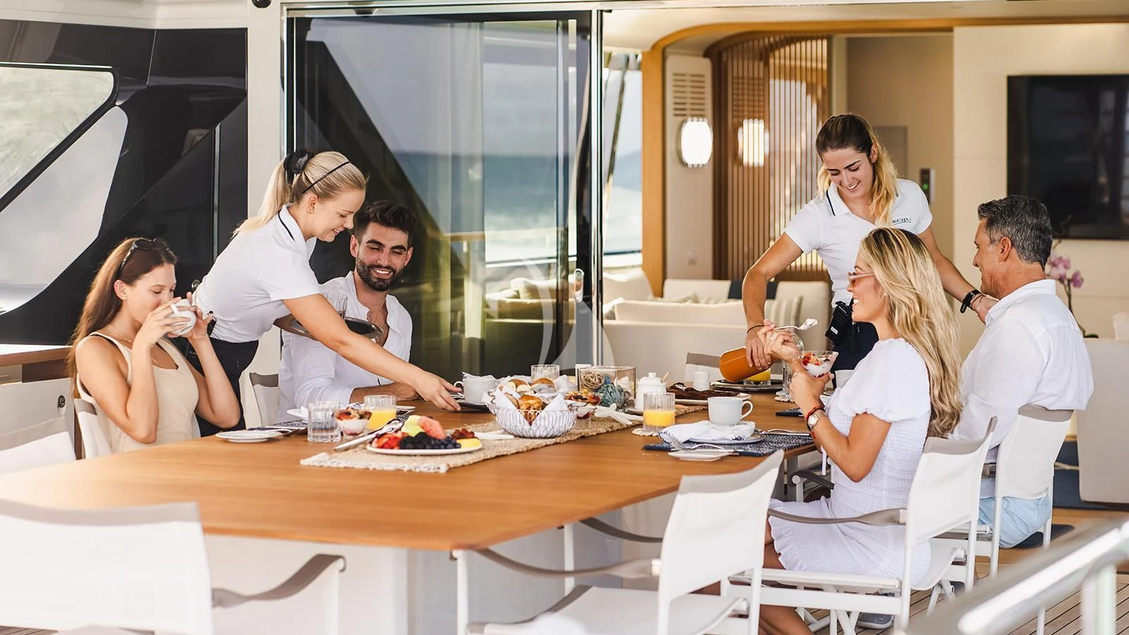 a group of people around a table aboard KOJU Yacht for Sale