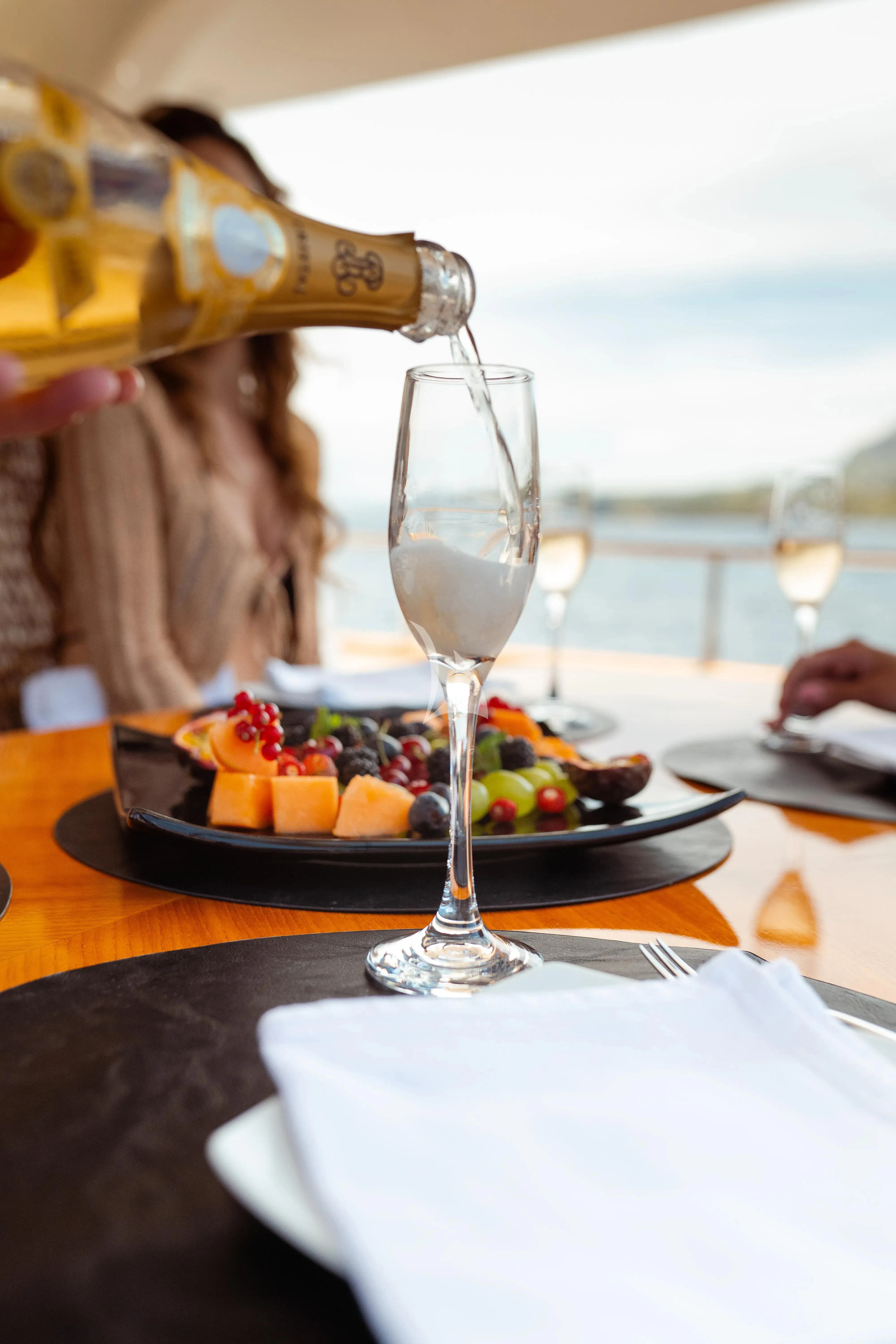 a glass of wine next to a plate of fruit aboard JAUNI Yacht for Sale
