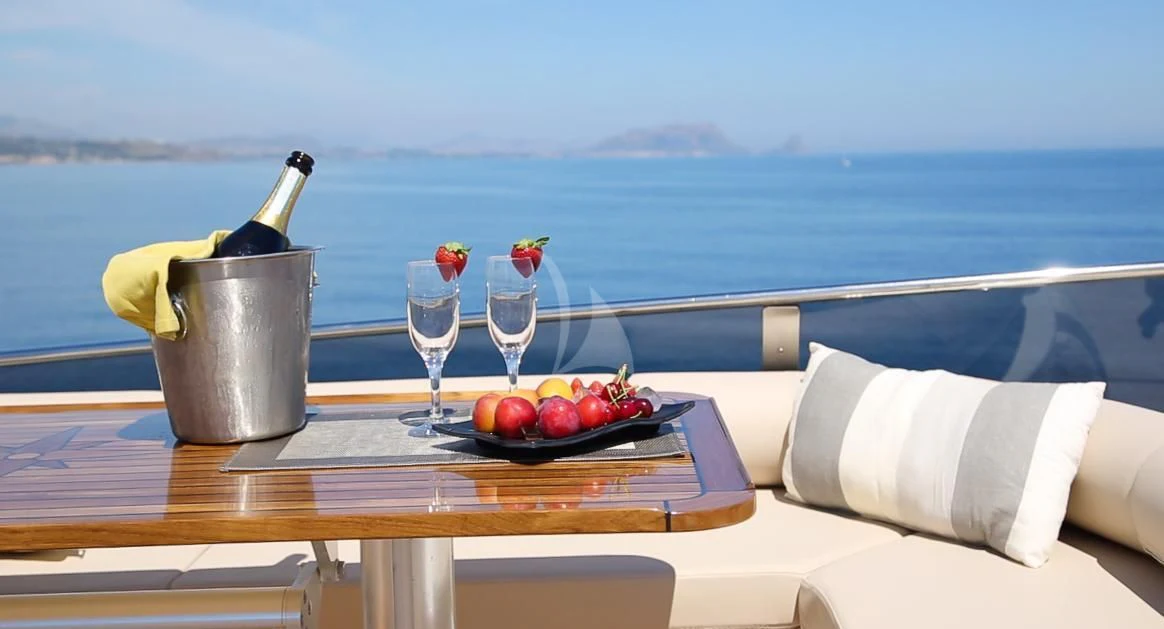 a table with a glass of wine and fruit on it aboard JAUNI Yacht for Sale