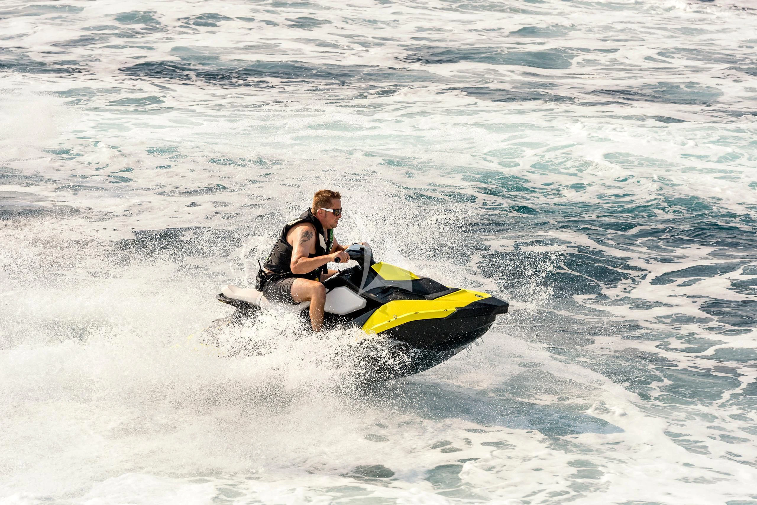a couple of people ride a jet ski in the water aboard ANTISAN Yacht for Charter