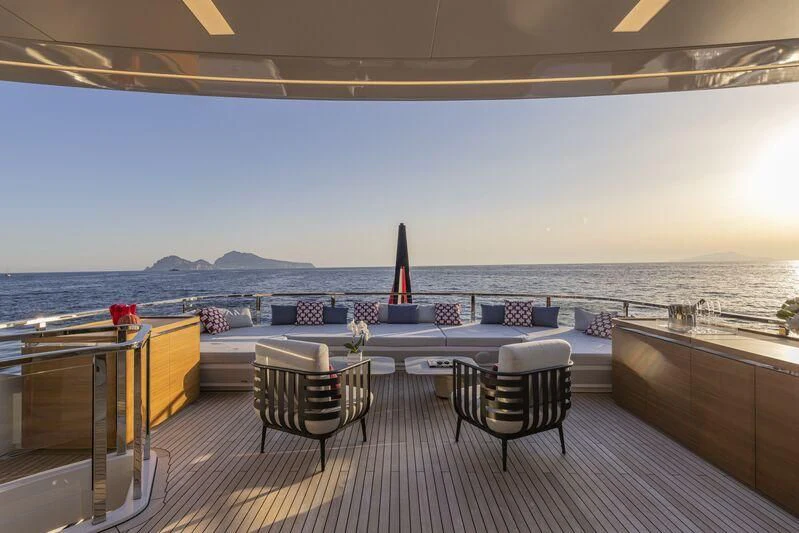 a deck with a view of the ocean and mountains in the background aboard ARIA SF Yacht for Sale