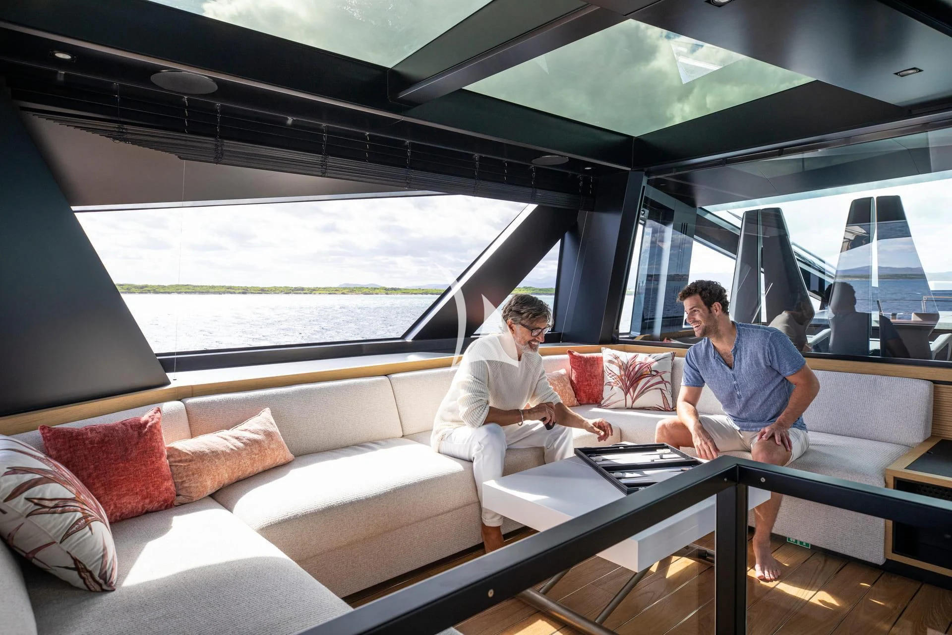 a couple of men sitting on a couch in a room with a large window aboard WHY 200 Yacht for Sale