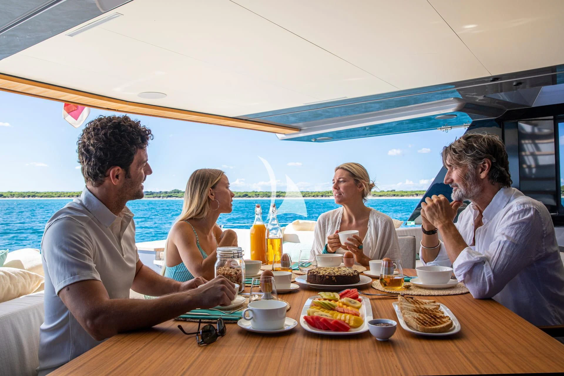 a group of people sitting around a table eating food aboard WHY 200 Yacht for Sale