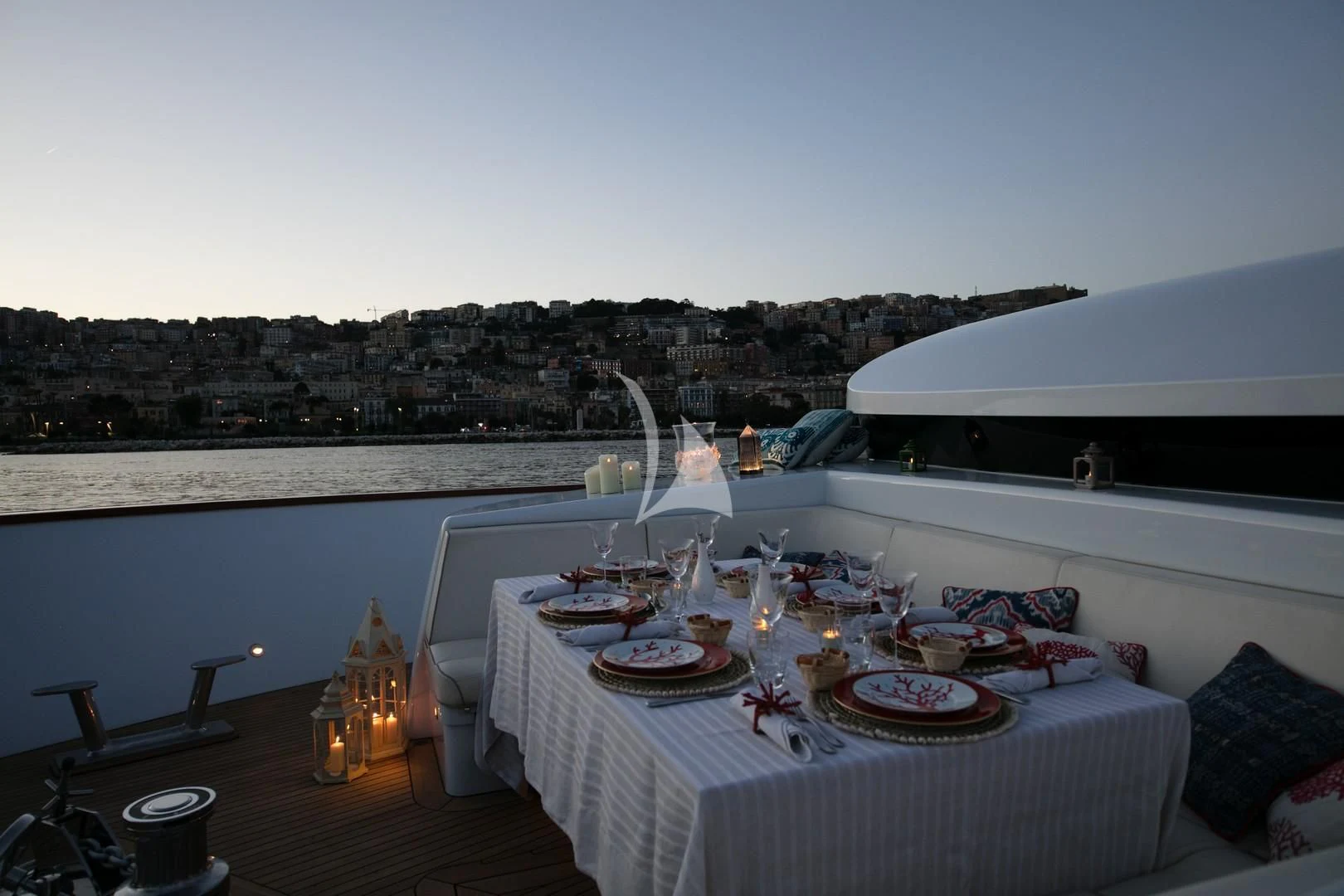 a table set with plates and candles on a balcony overlooking a body of water aboard ANGRA TOO Yacht for Sale