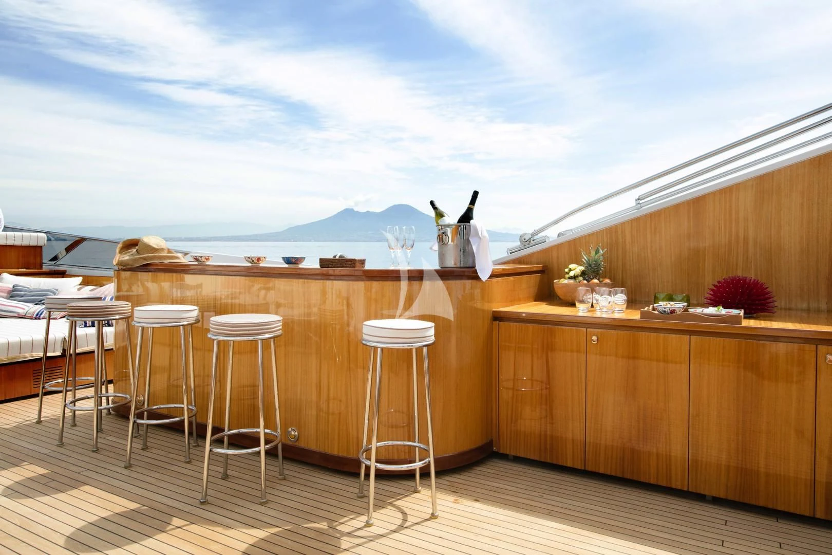 a wood table with stools and a view of the ocean aboard ANGRA TOO Yacht for Sale