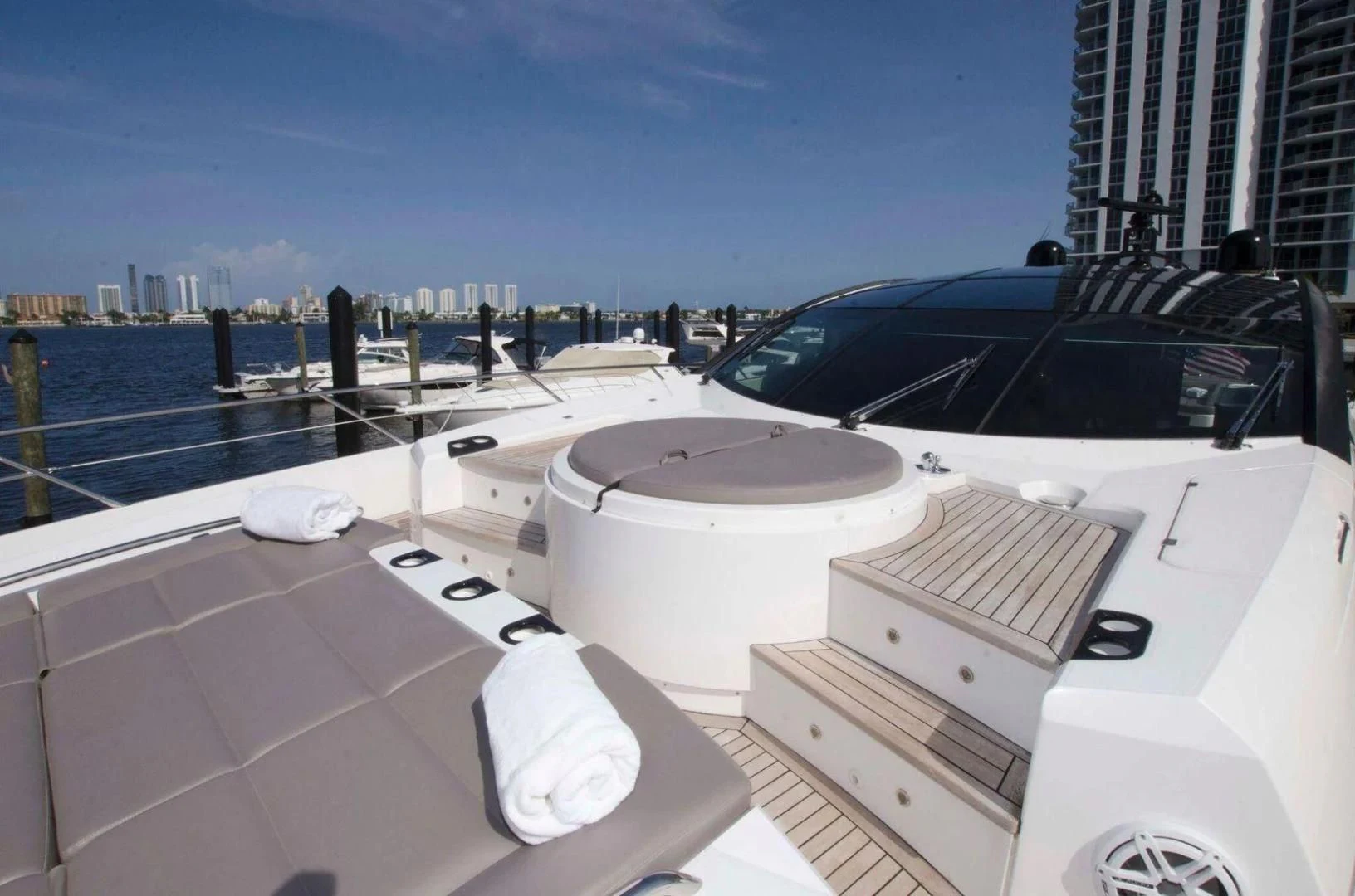 a deck with a large white lounge chair and a large city in the background aboard WOODEVER Yacht for Sale