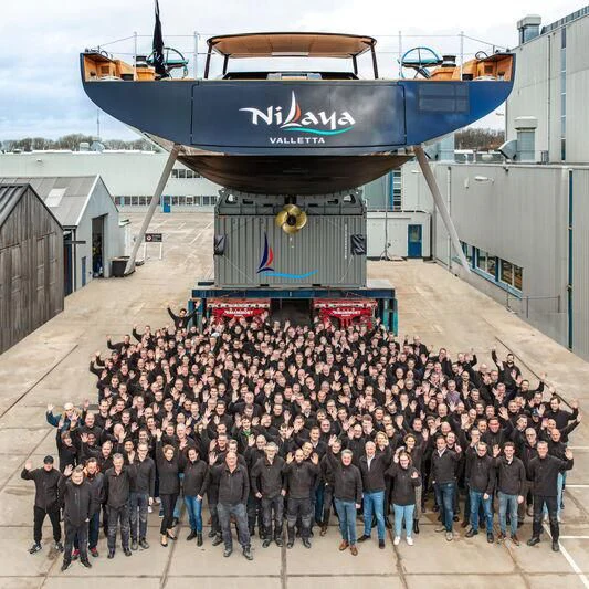 a large group of people standing in front of a large ship aboard NILAYA Yacht for Sale