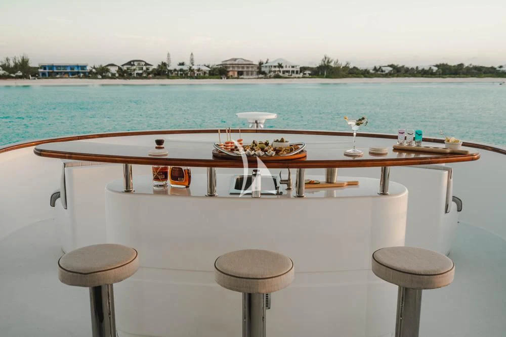 a table with chairs and a boat on it by a body of water aboard HEAVEN CAN WAIT Yacht for Charter