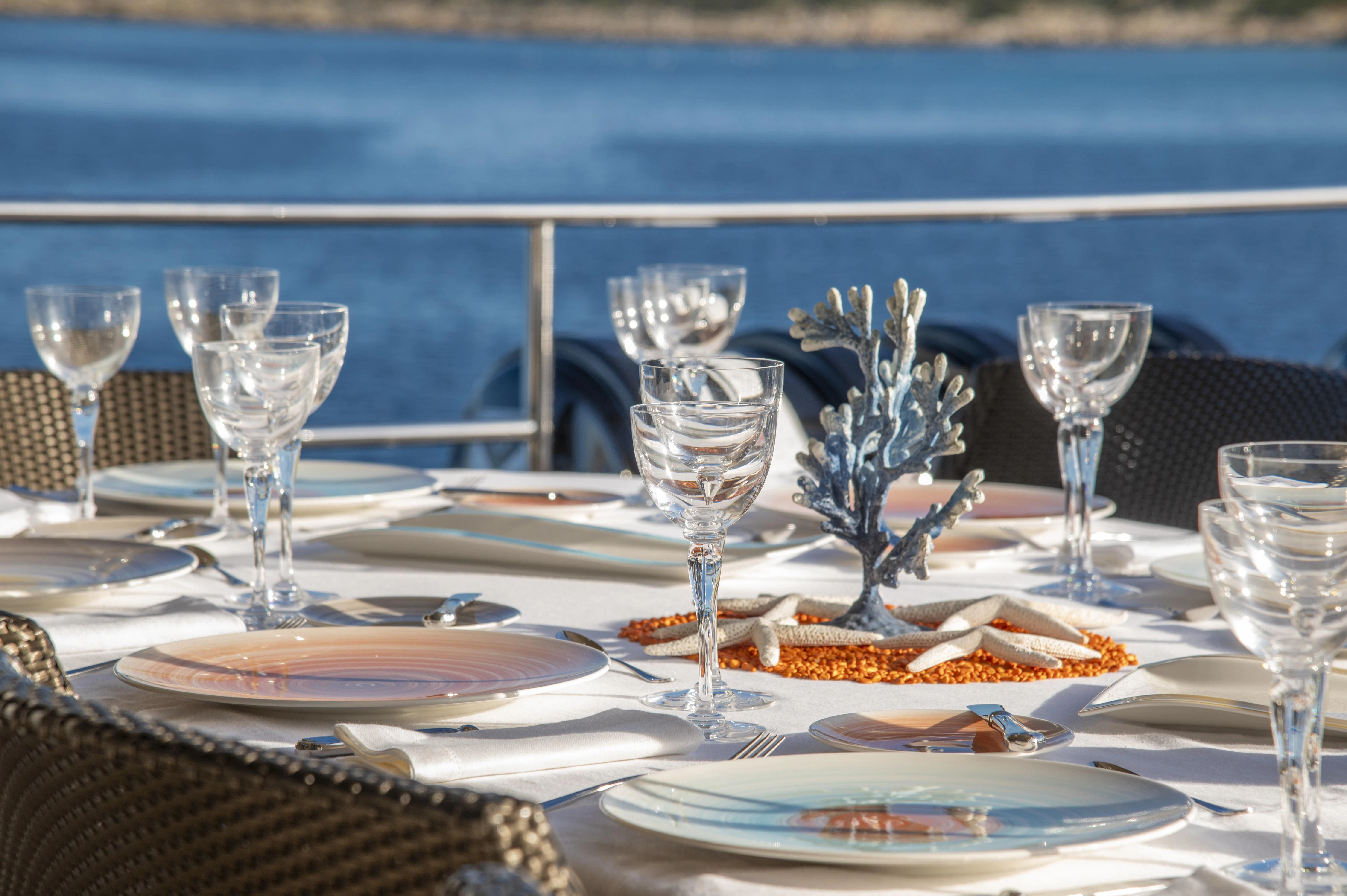 a table with wine glasses and plates aboard HOKULANI Yacht for Sale