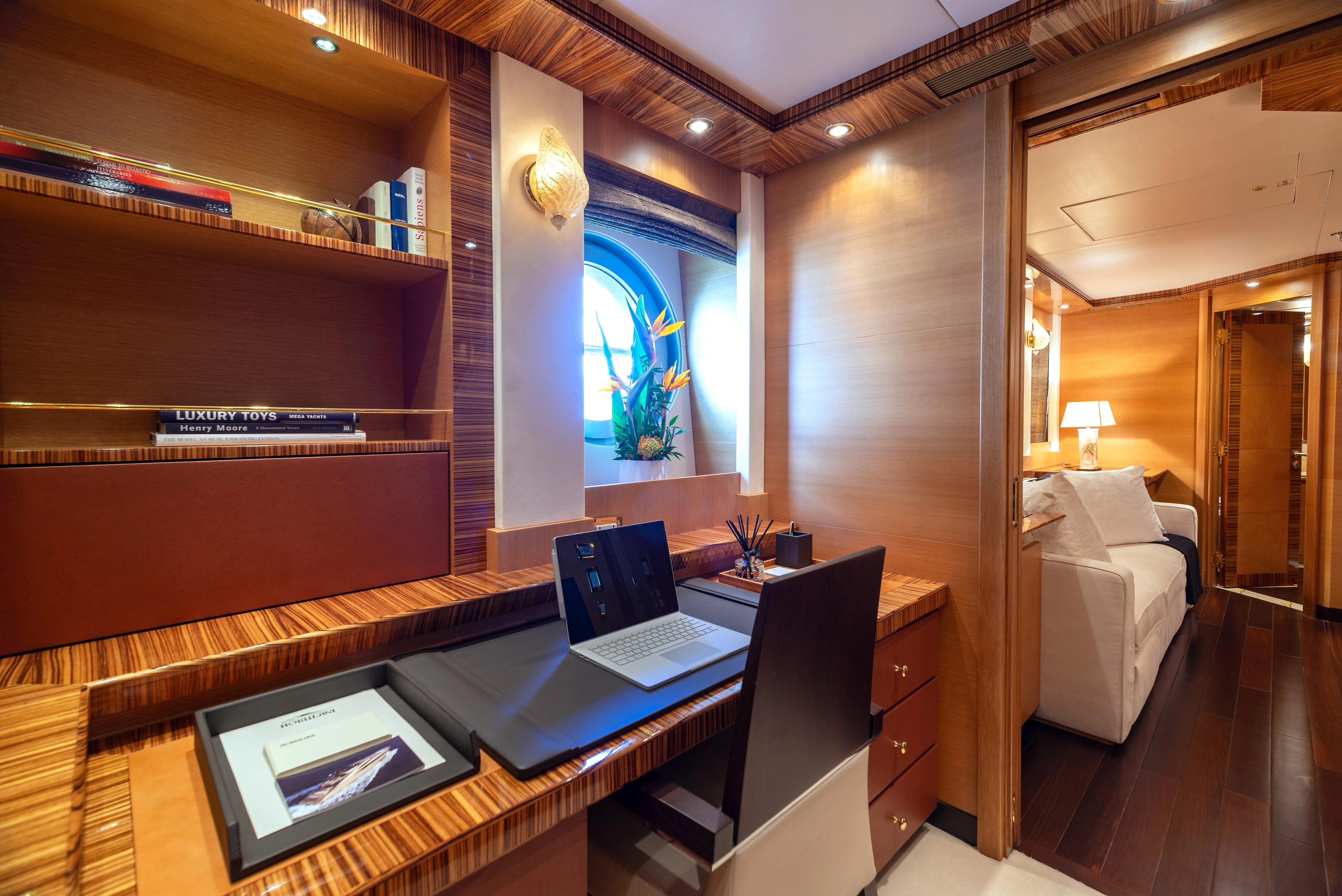 a room with a bed and a laptop on a desk aboard HOKULANI Yacht for Sale