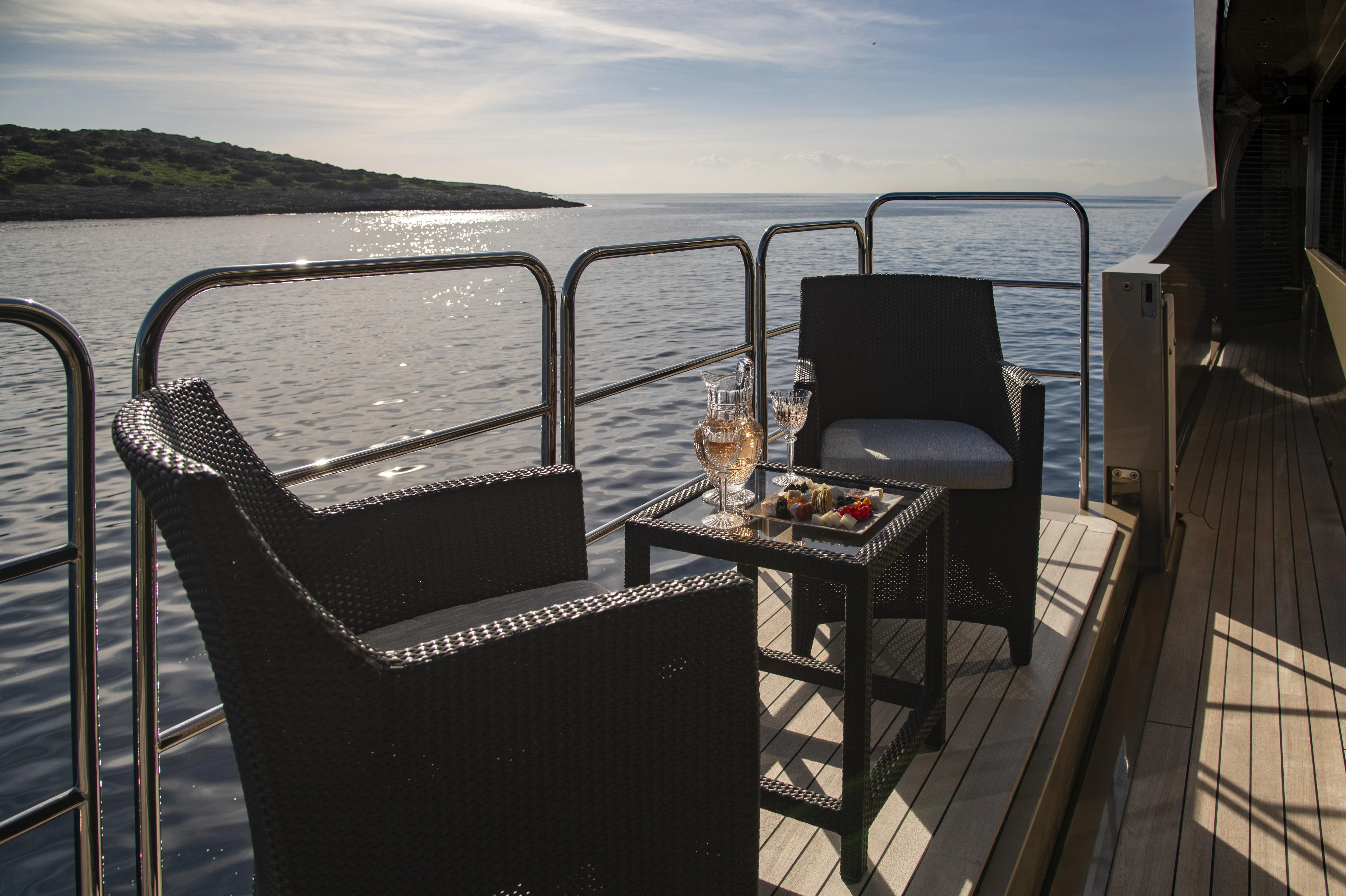 a balcony with a table and chairs on a deck overlooking the water aboard HOKULANI Yacht for Sale