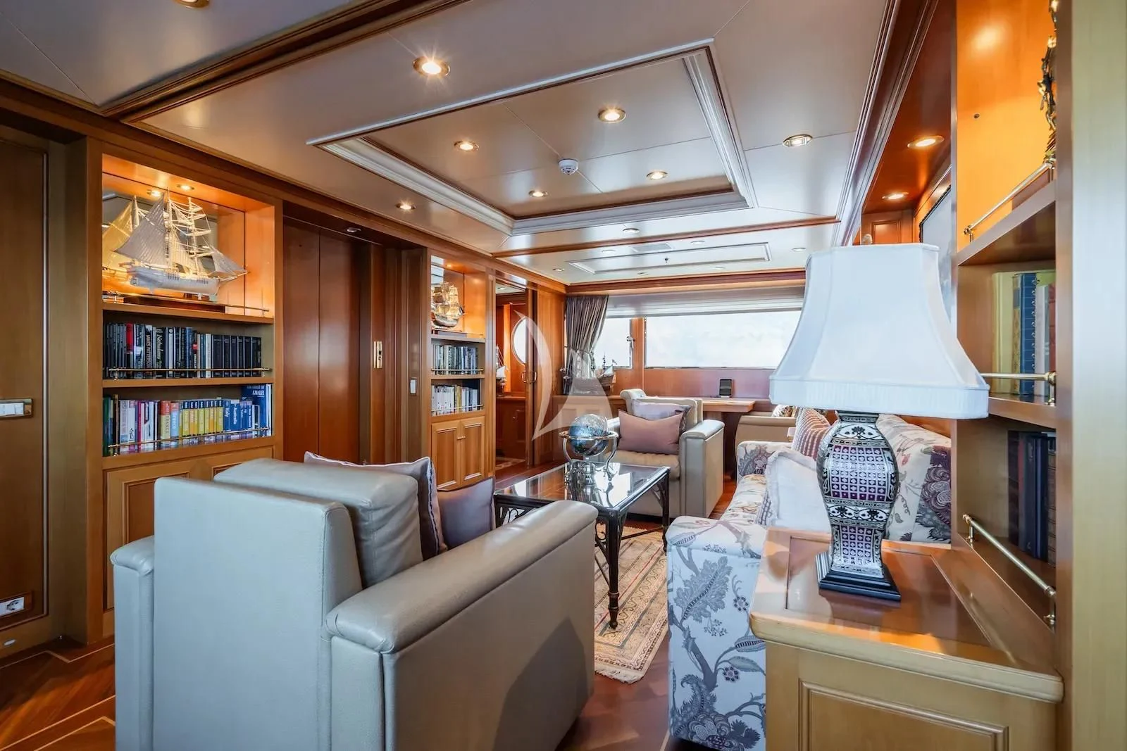 a living room with a book shelf and a lamp aboard TE MANU Yacht for Charter