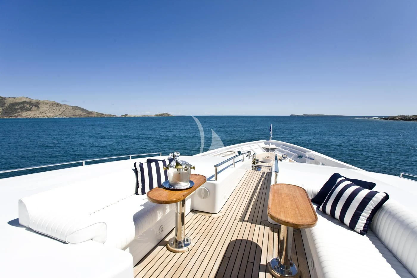 a large white bed with a table on it next to a body of water aboard TE MANU Yacht for Charter