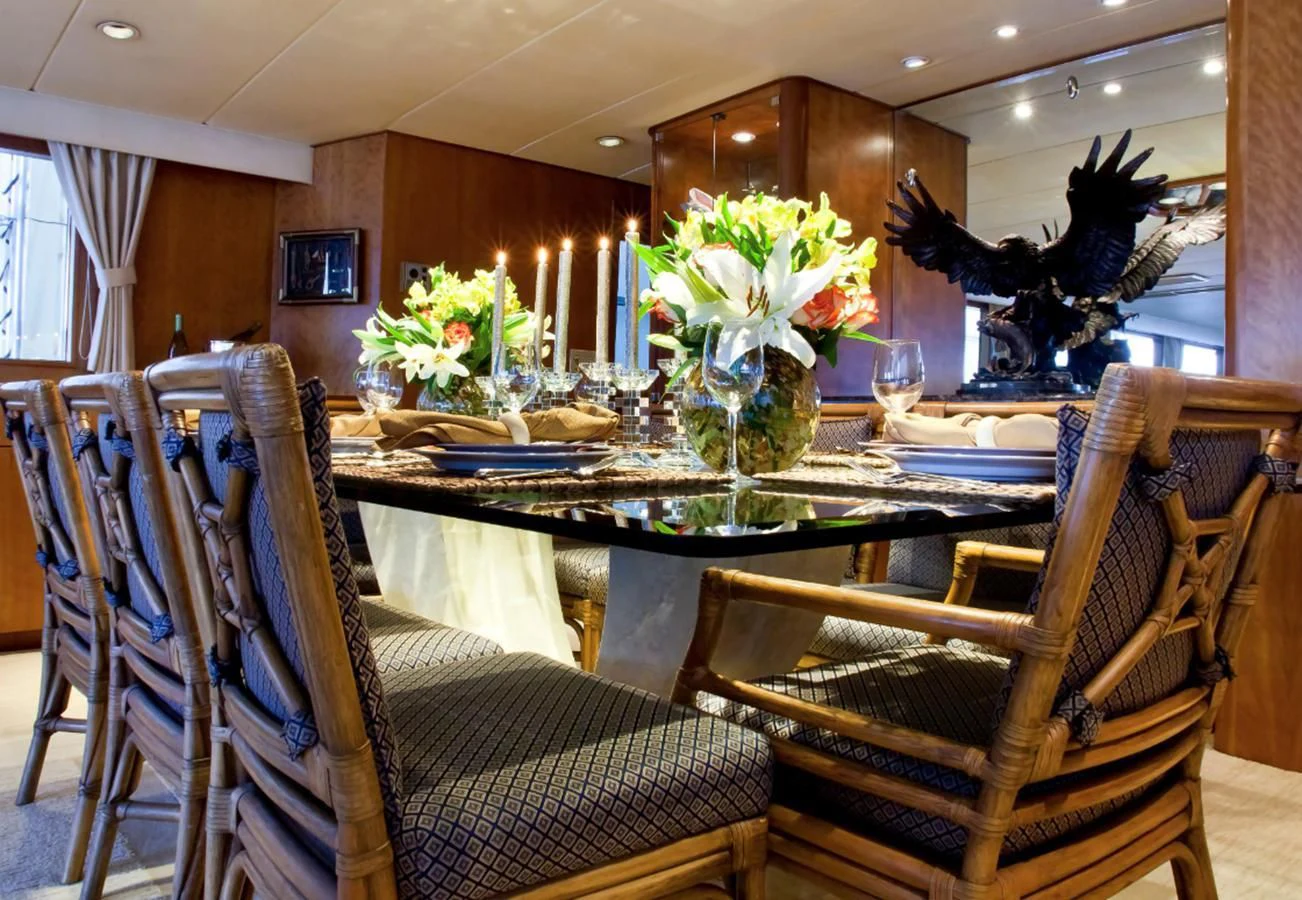 a dining room table with chairs and flowers aboard GOLDEN EAGLE Yacht for Sale