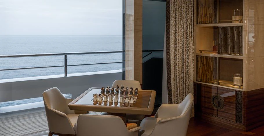 a table with a game console and a couch in a room with a window and bookshelves aboard ENERGY Yacht for Sale
