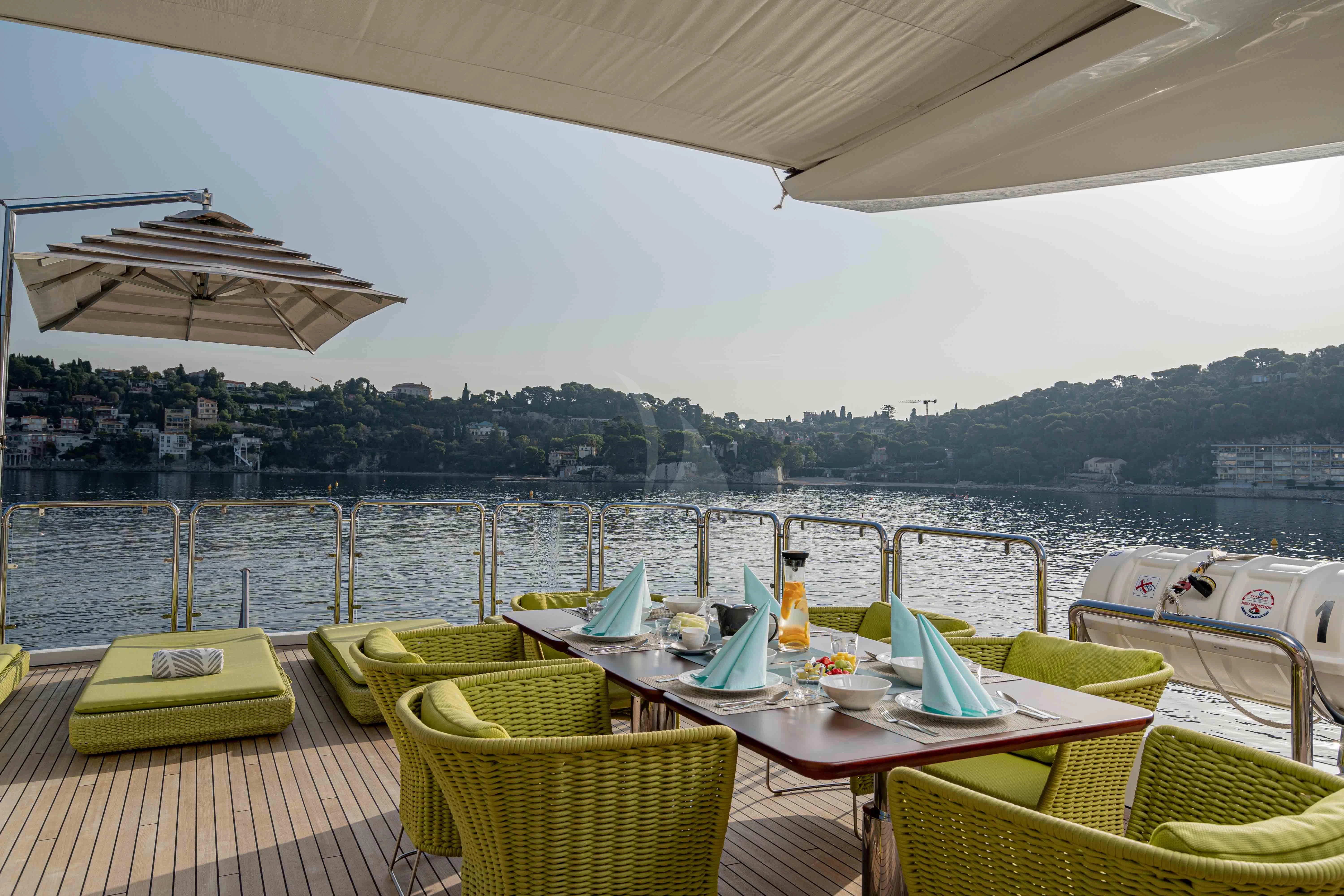 a table with chairs on it next to a body of water aboard EDESIA Yacht for Sale
