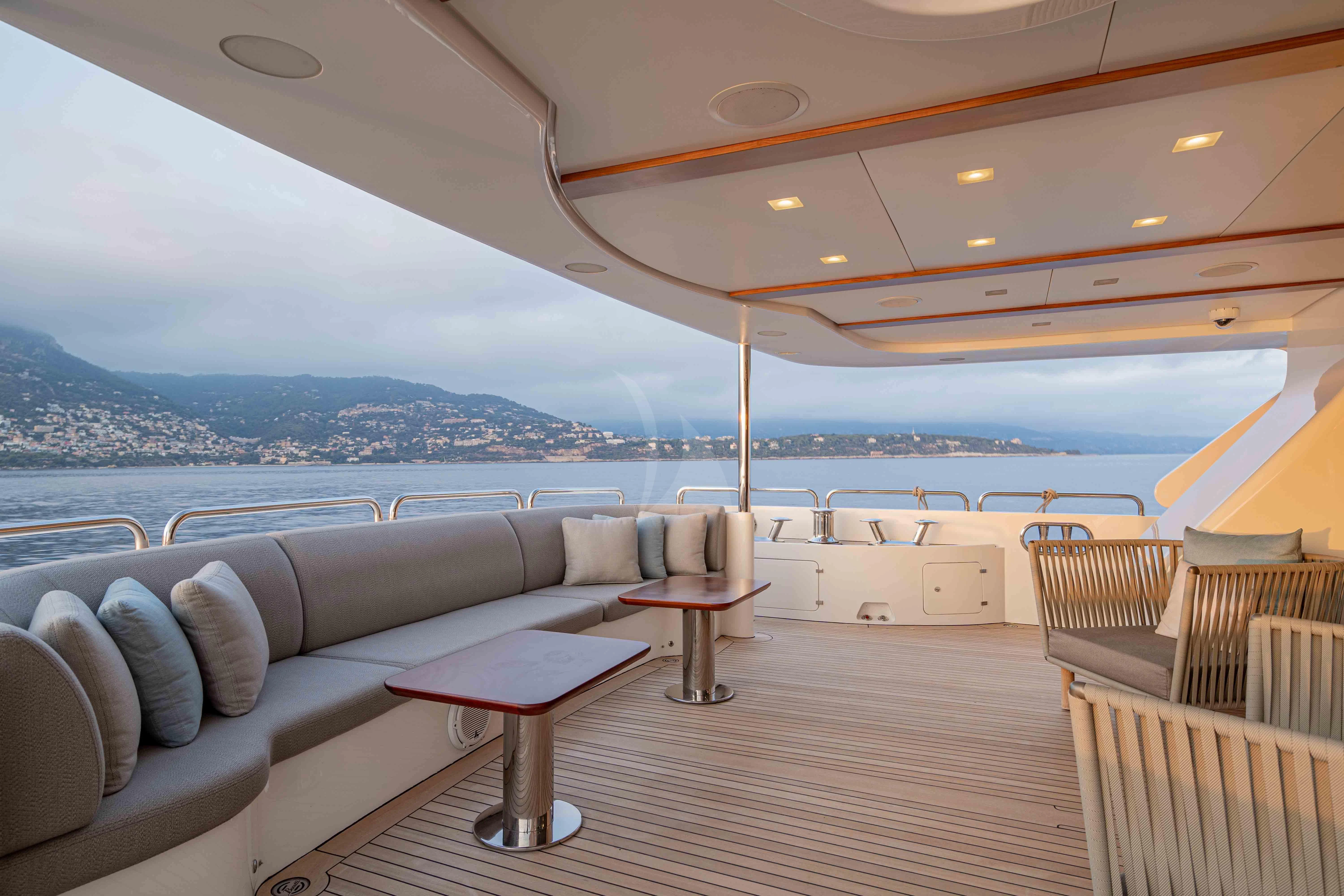 a boat deck with a view of the water and mountains in the background aboard EDESIA Yacht for Sale