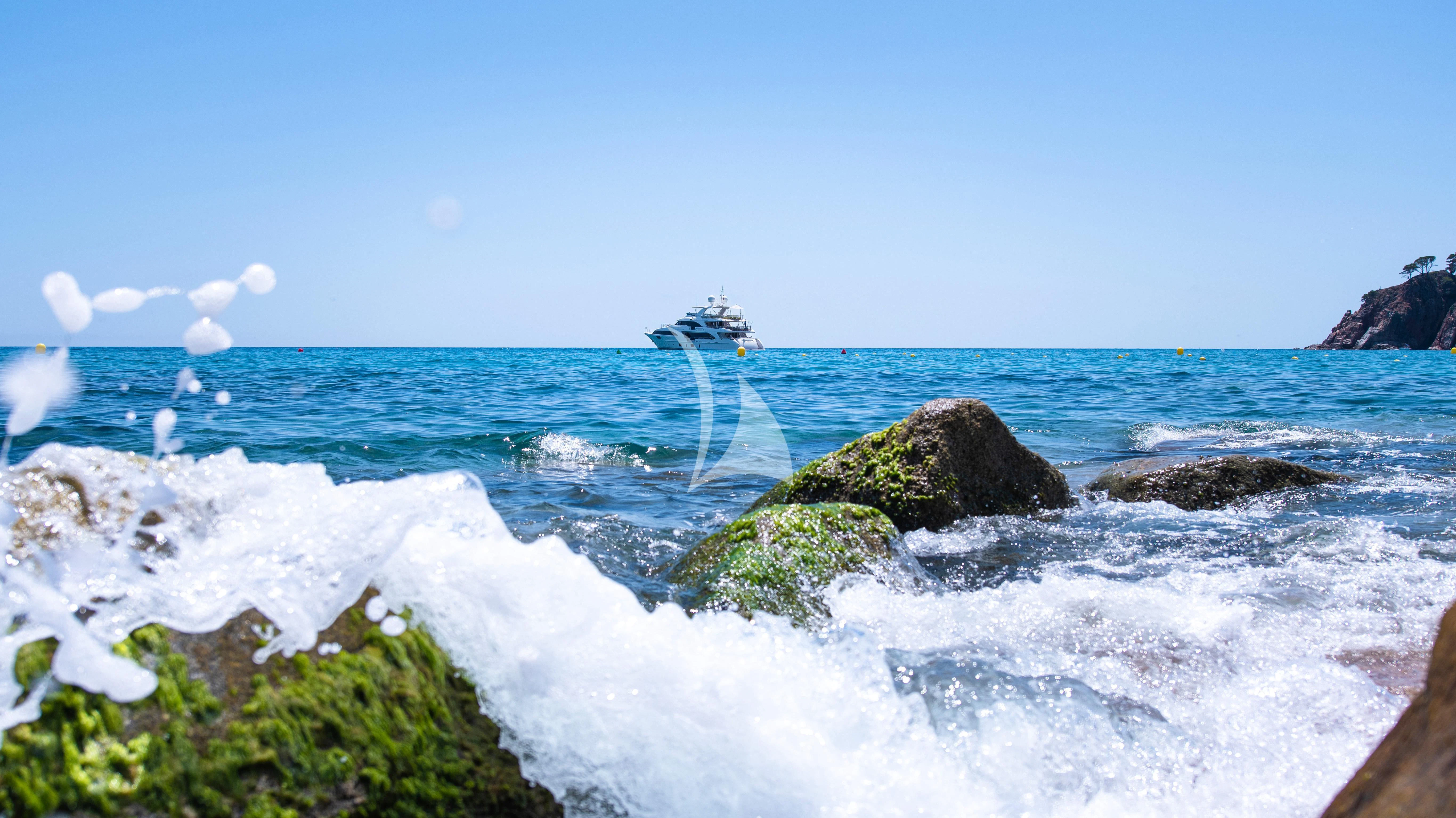 a body of water with rocks and a boat in the distance aboard EDESIA Yacht for Sale