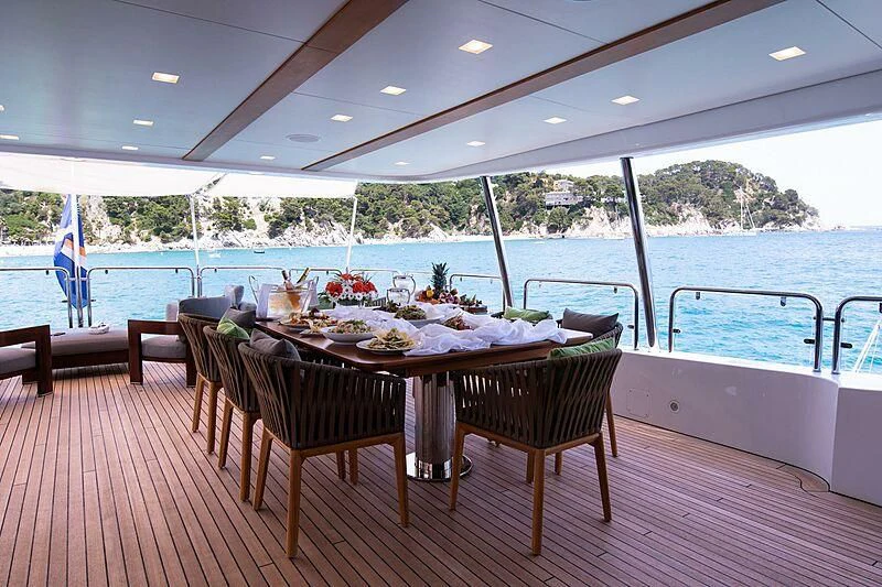 a table set for a meal on a deck overlooking a body of water aboard EDESIA Yacht for Sale