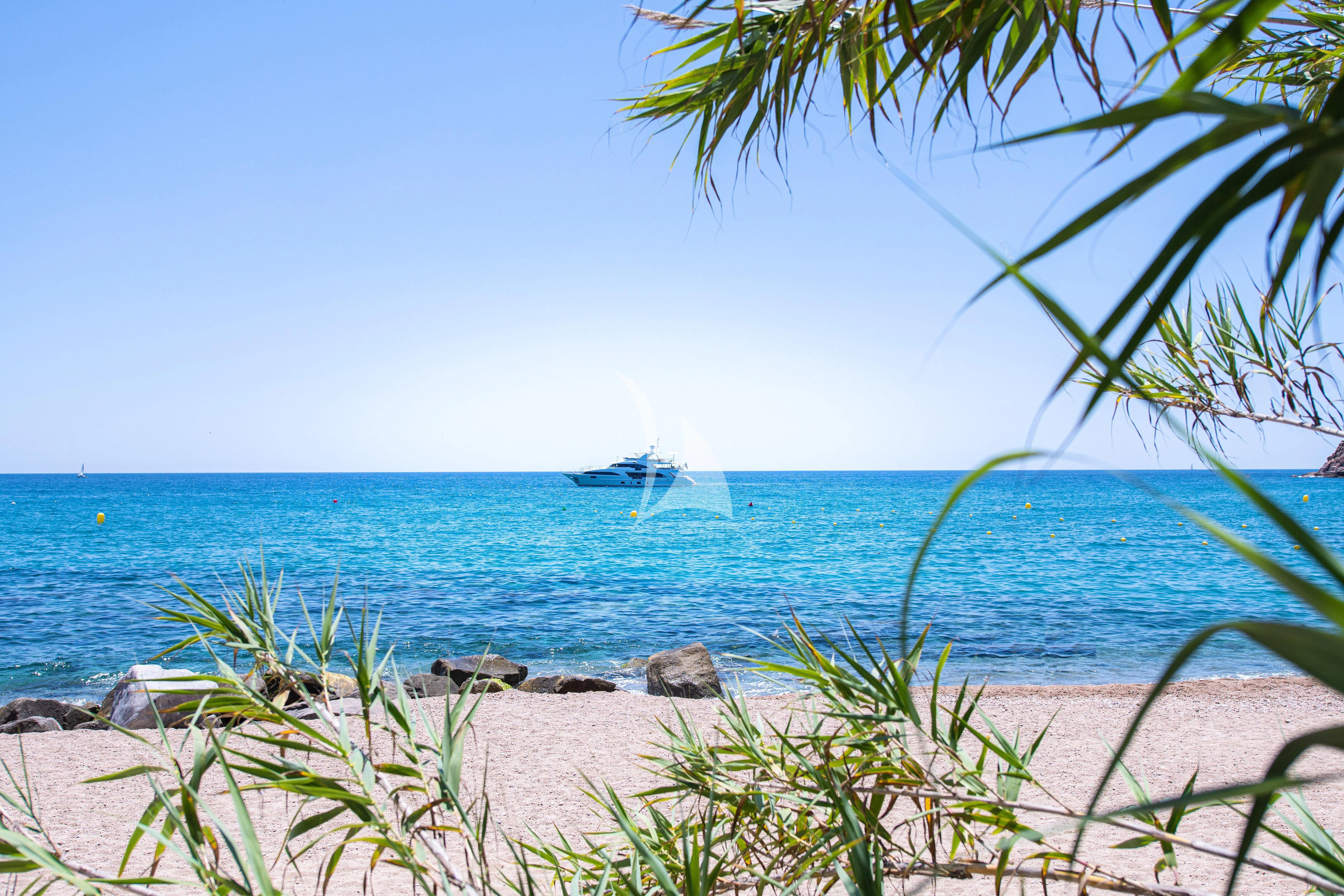 a beach with a boat in the distance aboard EDESIA Yacht for Sale