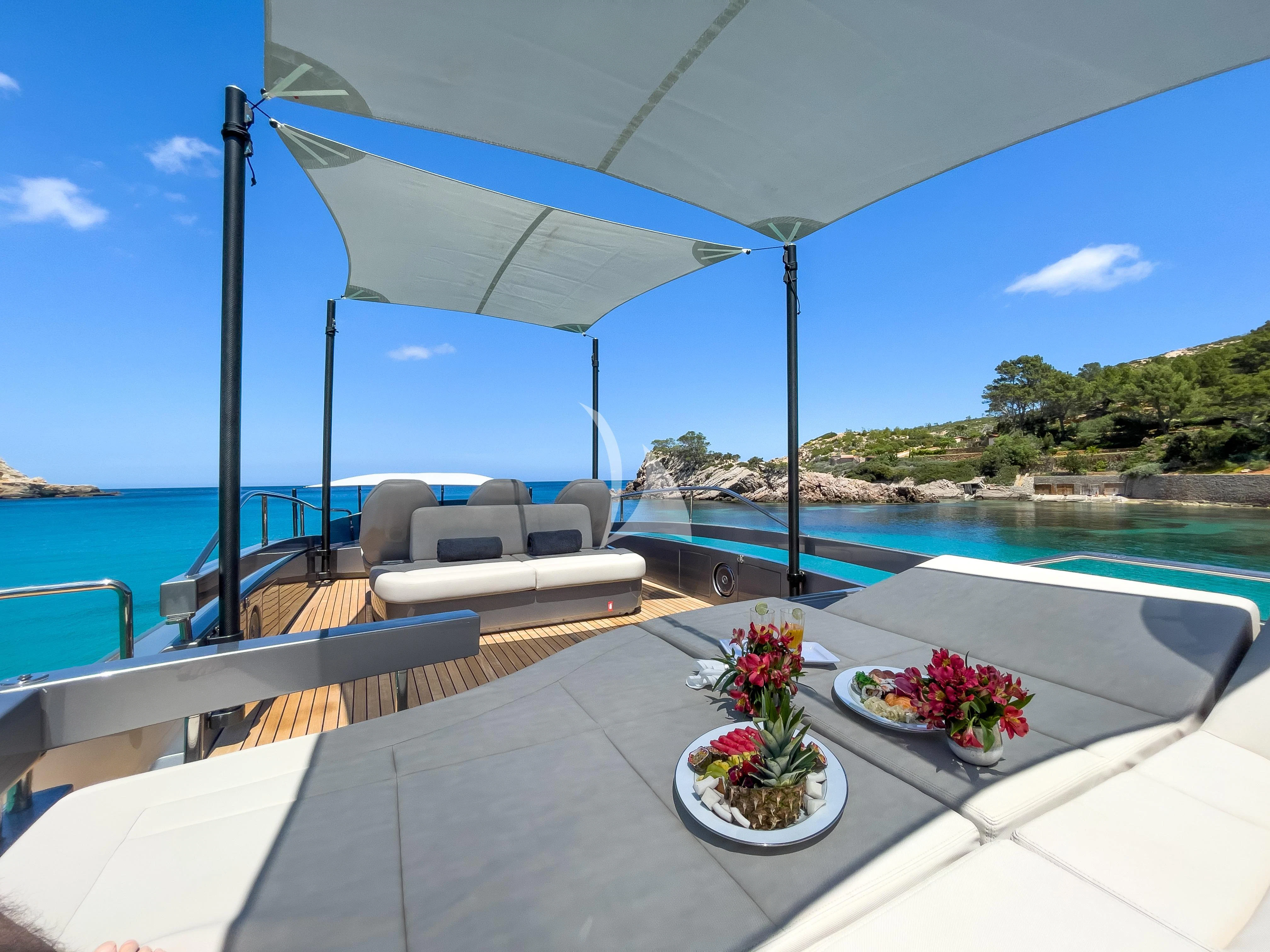a patio with a table and chairs on it by a body of water aboard BEYOND Yacht for Sale